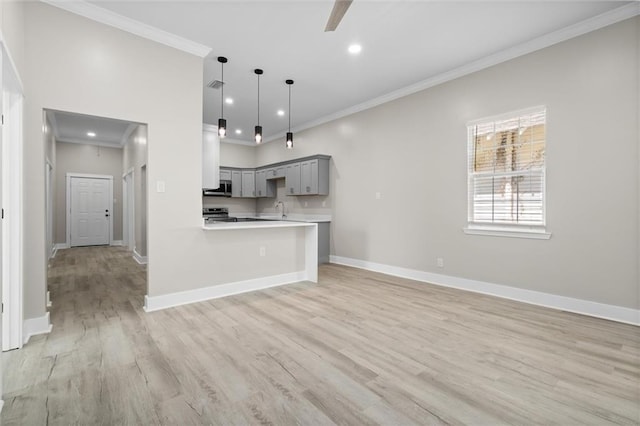 kitchen with a sink, light countertops, ornamental molding, and gray cabinetry