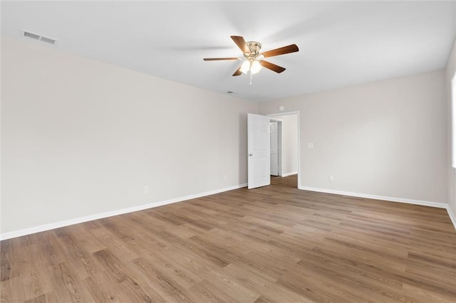 unfurnished room featuring a ceiling fan, wood finished floors, visible vents, and baseboards