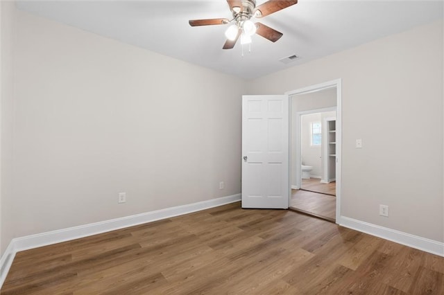 unfurnished bedroom with ceiling fan, wood finished floors, visible vents, and baseboards