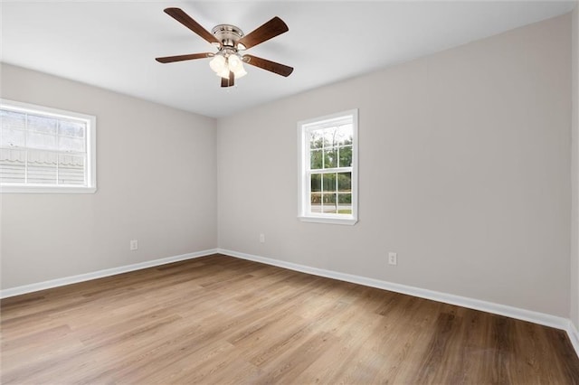 spare room featuring light wood-type flooring, a ceiling fan, and baseboards