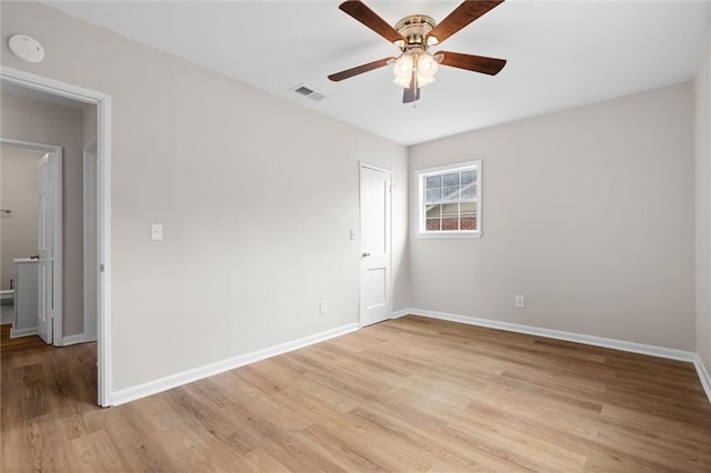 spare room featuring light wood-style floors, baseboards, visible vents, and a ceiling fan