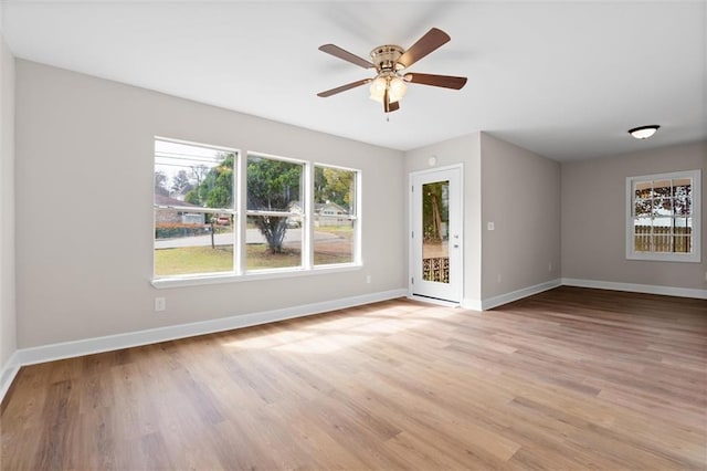 unfurnished room with light wood-style floors, a ceiling fan, and baseboards