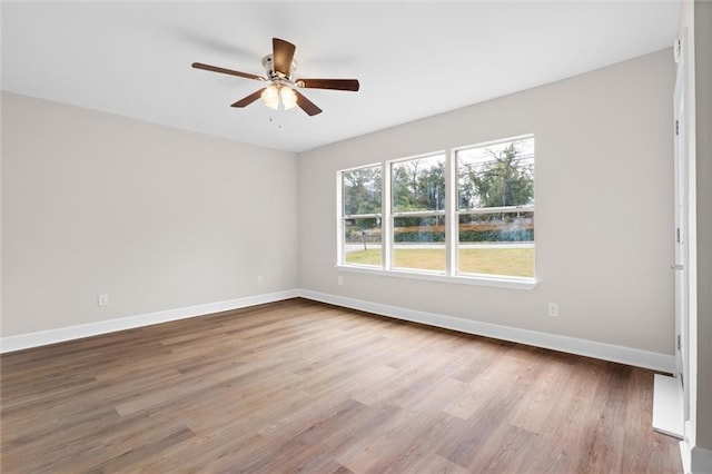 spare room featuring a ceiling fan, baseboards, and wood finished floors