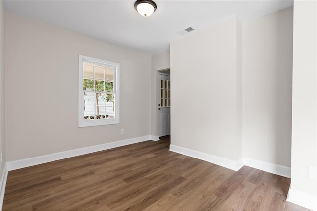 spare room with wood finished floors, visible vents, and baseboards