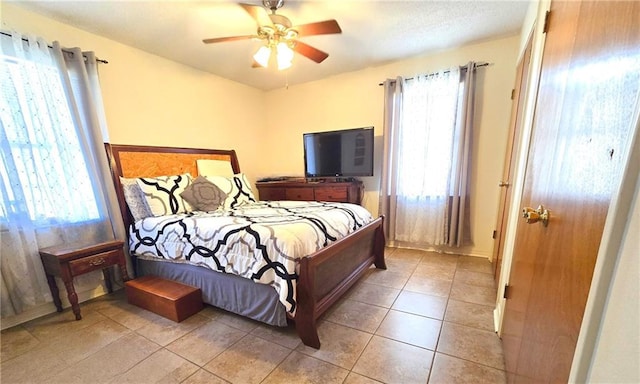 bedroom featuring ceiling fan, multiple windows, and light tile patterned floors