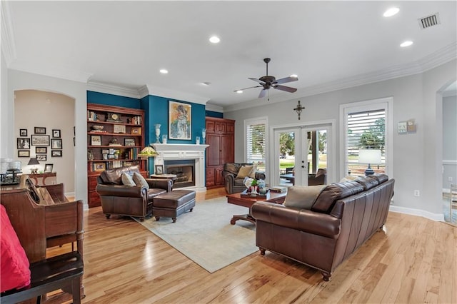 living room with crown molding, light hardwood / wood-style flooring, ceiling fan, and french doors