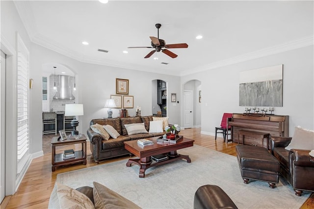 living room with ornamental molding, ceiling fan, and light hardwood / wood-style flooring