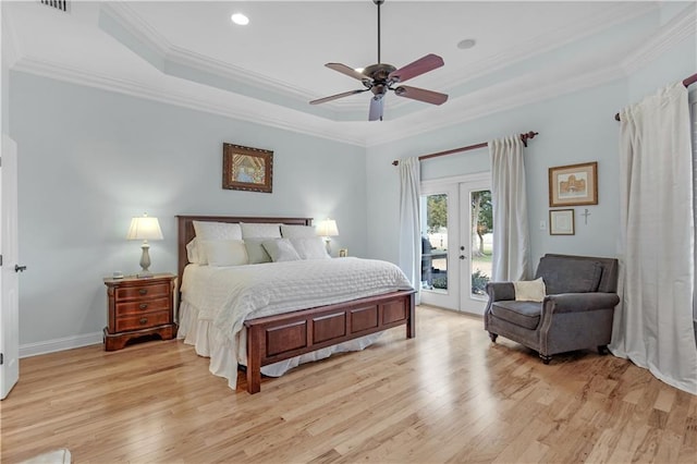 bedroom featuring crown molding, access to exterior, a tray ceiling, and light hardwood / wood-style flooring