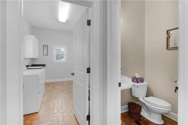 bathroom with toilet, sink, and washer and dryer