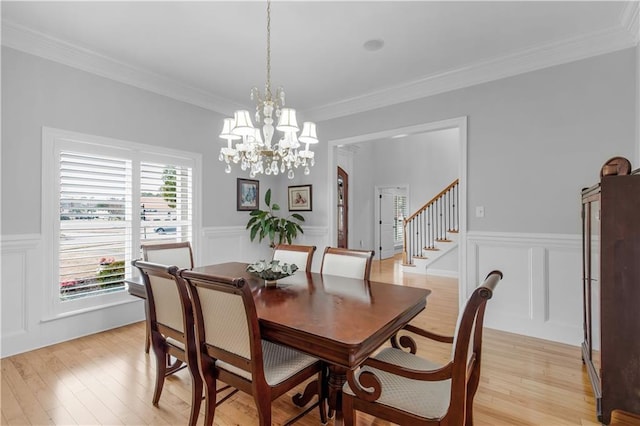 dining area with crown molding, a notable chandelier, and light hardwood / wood-style floors