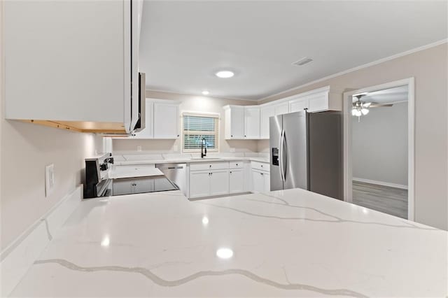 kitchen with white cabinets, stainless steel appliances, light stone countertops, and crown molding