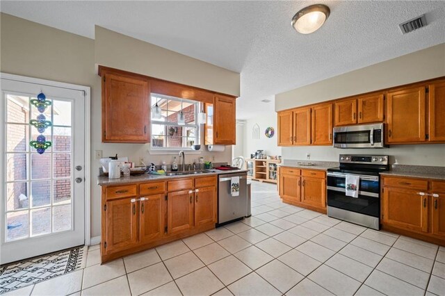 kitchen with sink, stainless steel appliances, light tile patterned flooring, and a textured ceiling