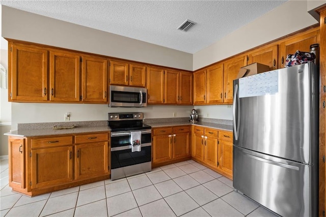 kitchen featuring a textured ceiling, stainless steel appliances, and light tile patterned flooring