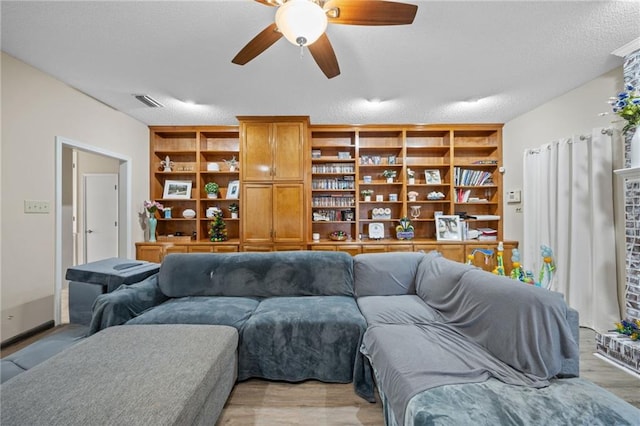 living room with a brick fireplace, ceiling fan, and light hardwood / wood-style flooring