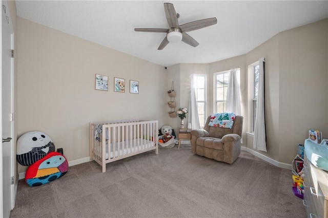 bedroom featuring ceiling fan, light carpet, and a crib