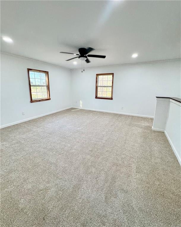 empty room featuring carpet flooring, ceiling fan, and crown molding