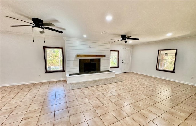 unfurnished living room with a wealth of natural light, light tile patterned floors, a textured ceiling, and ceiling fan