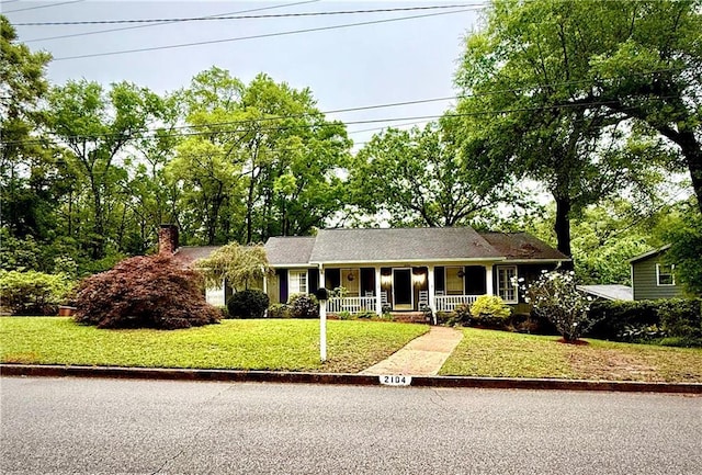 ranch-style house featuring a front yard, covered porch, and a chimney