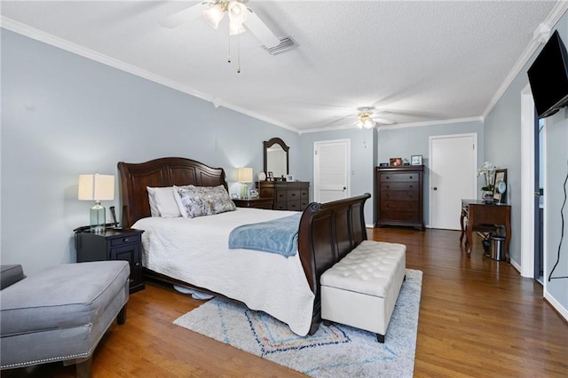 bedroom featuring crown molding, a ceiling fan, visible vents, and wood finished floors