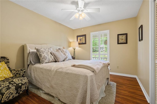 bedroom with baseboards, a ceiling fan, a textured ceiling, and dark wood-style floors