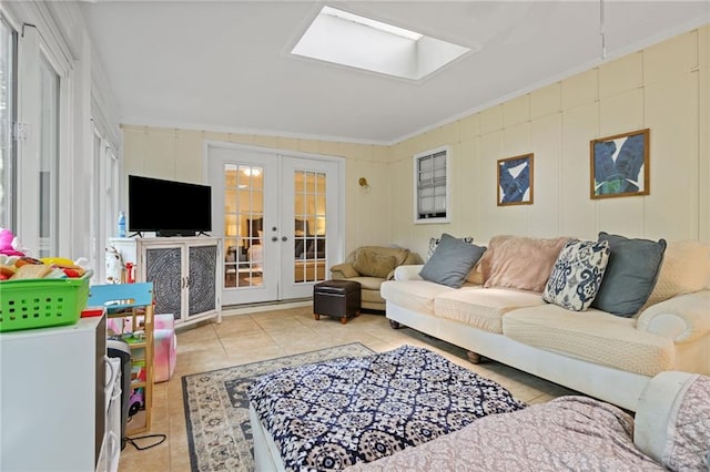 living area featuring french doors, ornamental molding, light tile patterned floors, and a skylight