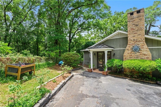 exterior space with board and batten siding, a standing seam roof, a chimney, and metal roof