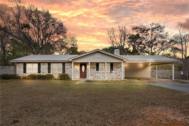 view of front facade with metal roof, an attached carport, concrete driveway, a yard, and a chimney