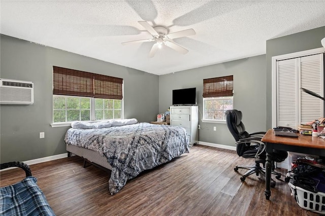 bedroom featuring a textured ceiling, baseboards, dark wood-style flooring, and an AC wall unit