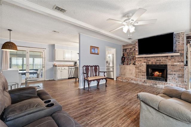 living room with ceiling fan, visible vents, dark wood-type flooring, and a textured ceiling