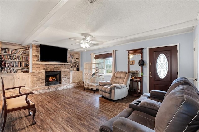 living room featuring dark wood-style floors, built in shelves, beamed ceiling, a textured ceiling, and a fireplace