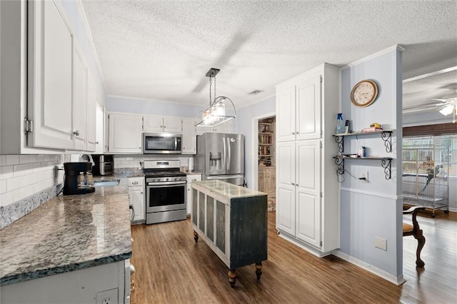 kitchen featuring white cabinets, dark stone counters, wood finished floors, hanging light fixtures, and stainless steel appliances
