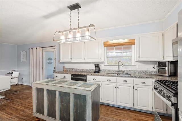 kitchen featuring gas stove, a sink, decorative light fixtures, and white cabinets