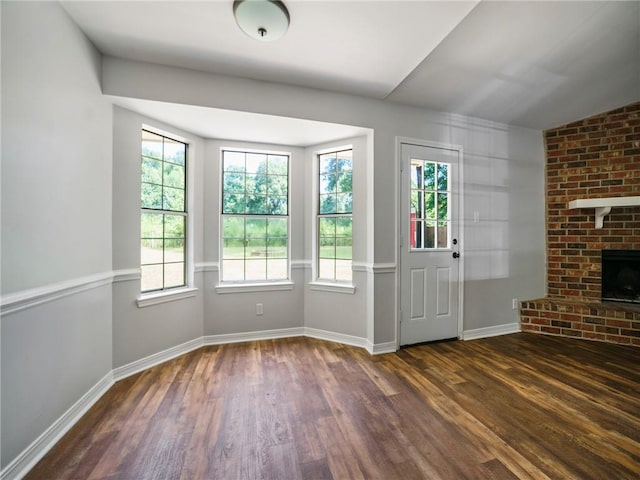 interior space featuring a fireplace, vaulted ceiling, dark hardwood / wood-style flooring, and plenty of natural light