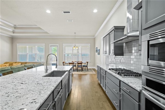 kitchen featuring pendant lighting, crown molding, appliances with stainless steel finishes, and wall chimney exhaust hood