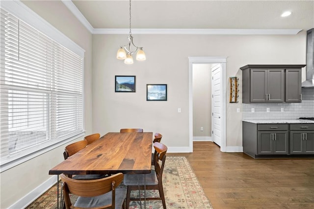 dining room with a notable chandelier, ornamental molding, and dark hardwood / wood-style floors