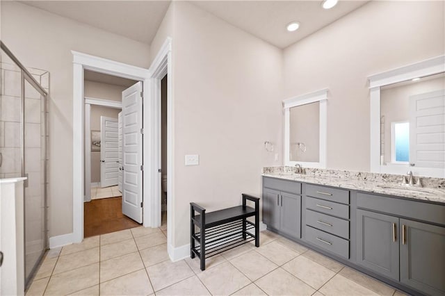 bathroom featuring a shower with shower door, vanity, and tile patterned floors