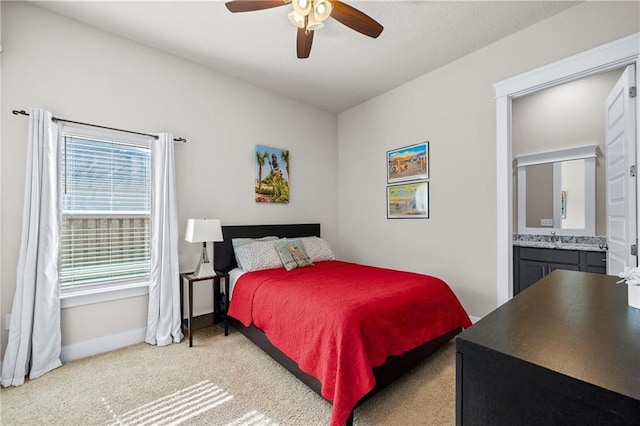 carpeted bedroom with ceiling fan, sink, and ensuite bath