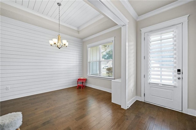 doorway with dark hardwood / wood-style floors, a chandelier, crown molding, and wood walls