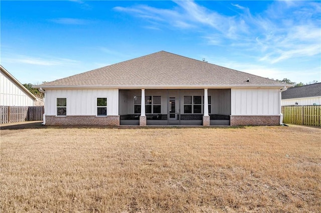 rear view of property featuring a sunroom and a yard