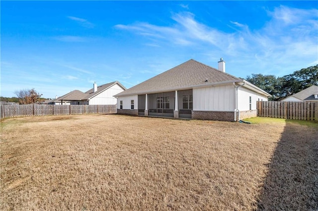 rear view of house featuring a yard and a sunroom