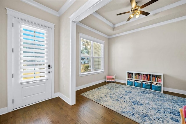 doorway to outside with ceiling fan, dark wood-type flooring, ornamental molding, and a raised ceiling