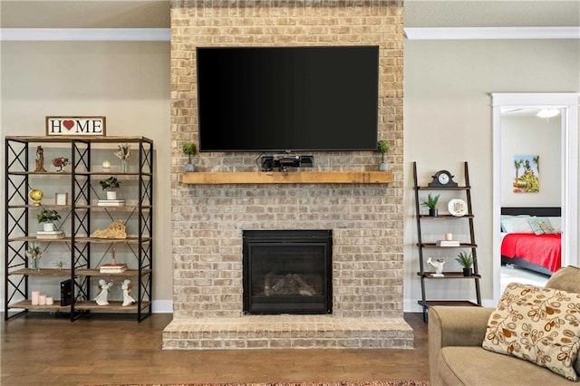 living room with dark hardwood / wood-style flooring, crown molding, and a fireplace