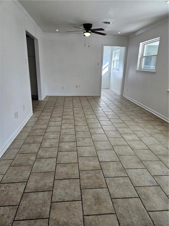 spare room featuring ceiling fan, crown molding, and light tile patterned flooring