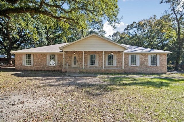 ranch-style house featuring covered porch and a front yard