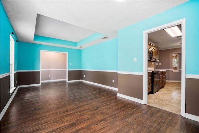 empty room featuring dark hardwood / wood-style flooring and a tray ceiling