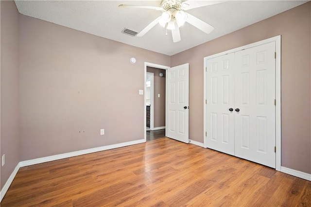 unfurnished bedroom featuring ceiling fan, light hardwood / wood-style floors, a textured ceiling, and a closet