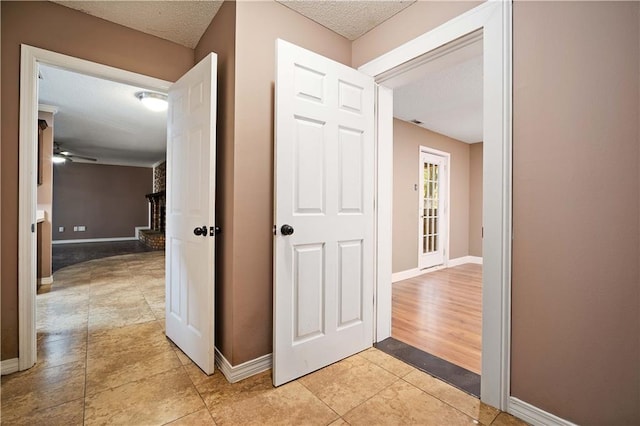 hallway with light wood-type flooring and a textured ceiling