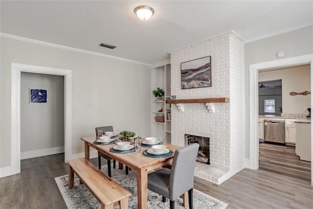 dining area featuring a brick fireplace, ornamental molding, and hardwood / wood-style floors