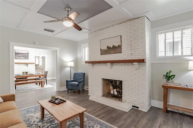 living room with coffered ceiling, a brick fireplace, ceiling fan, and dark wood-type flooring