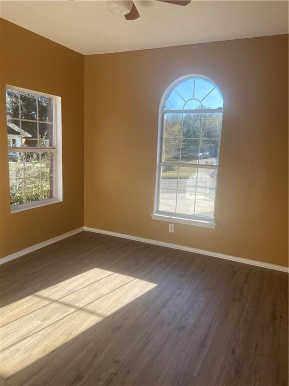 empty room featuring dark hardwood / wood-style flooring, plenty of natural light, and ceiling fan